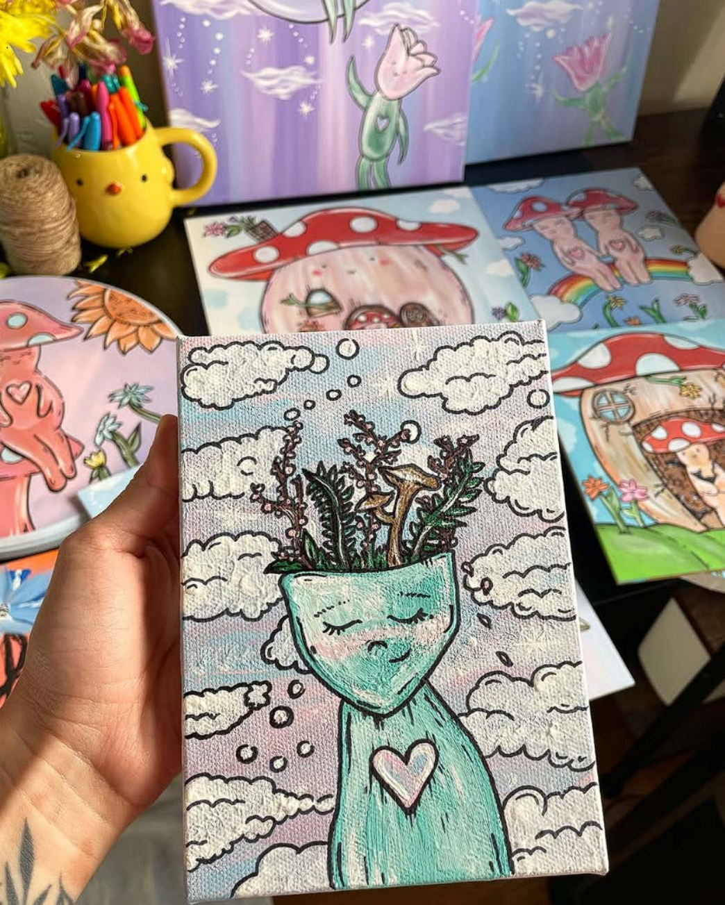 Hand holding a whimsical character with plants growing from its head